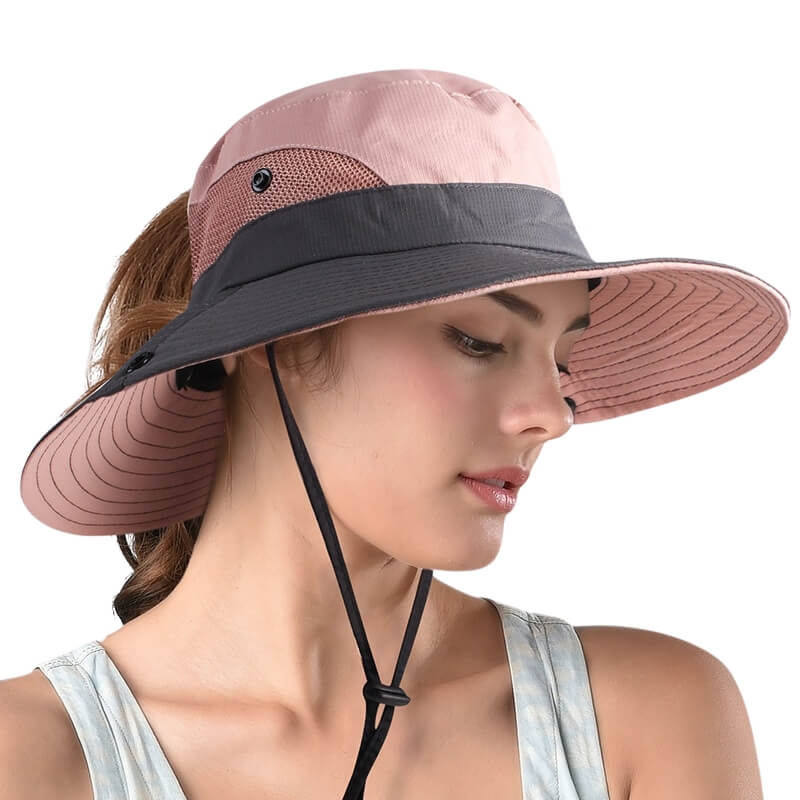 Femme portant un chapeau SunShade rose et gris à large bord, vue de face.