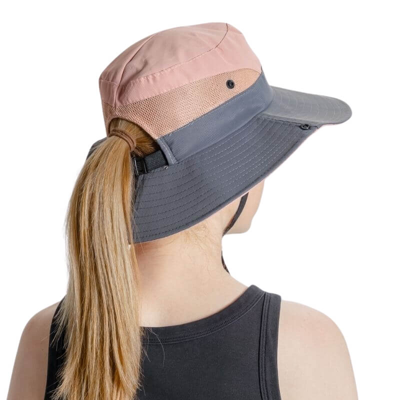 Femme de dos avec un chapeau de soleil SunShade rose à ouverture pour queue de cheval.