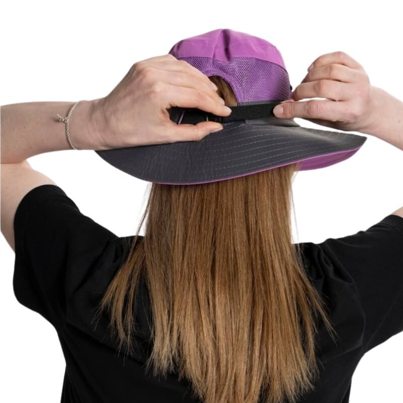Femme ajustant la fermeture arrière d’un chapeau violet SunShade à maille respirante.