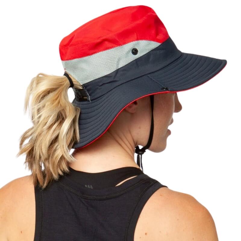 Femme de dos avec un chapeau de soleil rouge et bleu à ouverture pour queue de cheval.