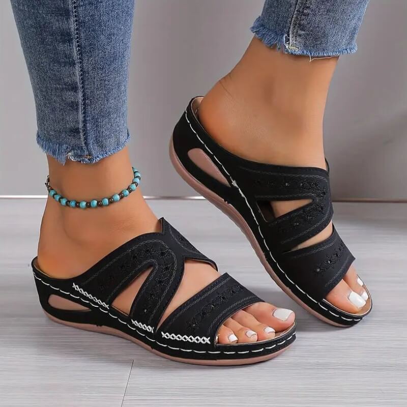 Femme portant des sandales noires à couture blanche et talon ergonomique, vue de côté avec jean frangé.