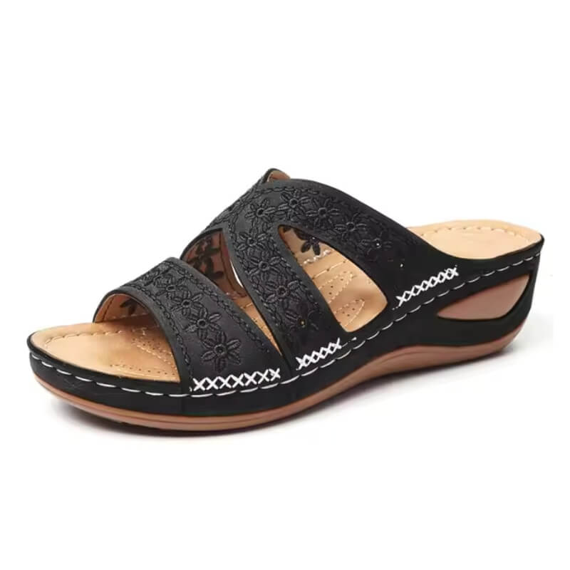 Sandale noire pour femme avec motif fleuri et semelle compensée, présentée sur fond blanc.