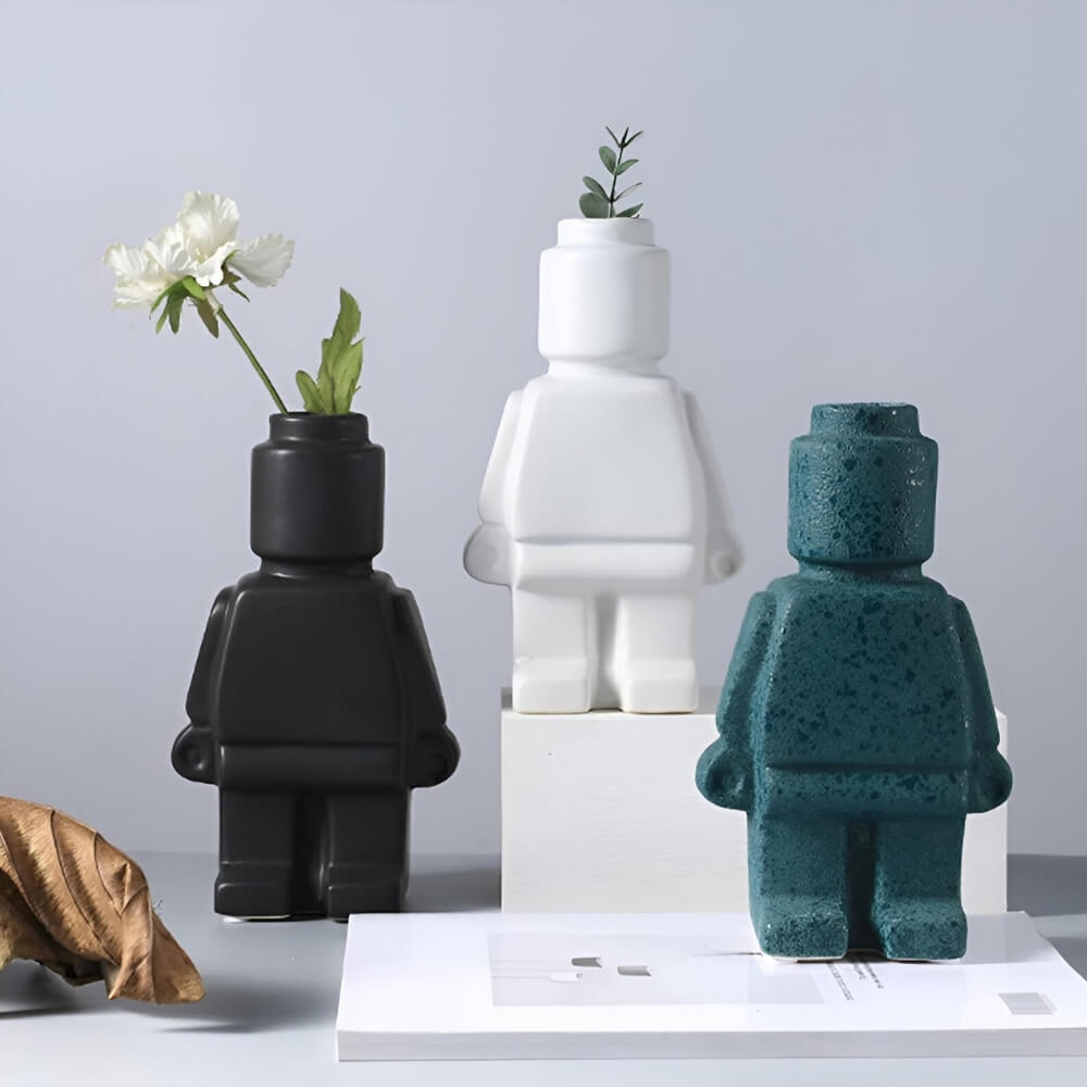 Trois vases LEGO noir, blanc et vert en décoration florale sur une table moderne